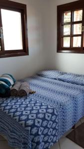 a bedroom with a bed with a blue comforter and a window at Quarto Suíte Itapoá - SC in Itapoa