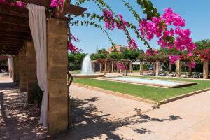 einen Brunnen inmitten eines Parks mit rosa Blumen in der Unterkunft Aparthotel Ciudad Laurel in Cala Millor + 37 Fotos