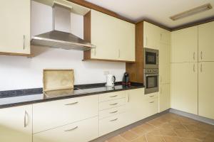 a kitchen with white cabinets and a stove top oven at Seagull House in Quinta do Lago