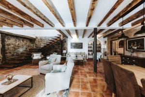 a living room with white furniture and a stone wall at Posada del tiempo in Villavieja del Lozoya