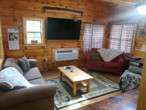 uma sala de estar com sofás e uma televisão de ecrã plano em The Hampton - An Amish Built Deluxe Log Cabin em Genoa