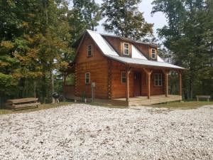 a log cabin in the middle of a gravel driveway at The Hampton - An Amish Built Deluxe Log Cabin in Genoa +13 photos