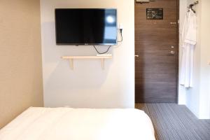 東京的住宿－The Light Inn - Vacation STAY 94702，一间设有床铺和墙上电视的房间