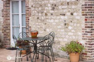 a patio table and chairs in front of a brick wall at Les Chambres du Chataignier in Léry