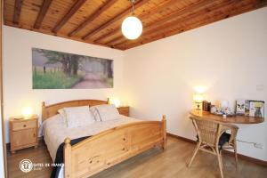 1 dormitorio con cama de madera y escritorio en Les Chambres du Chataignier, en Léry