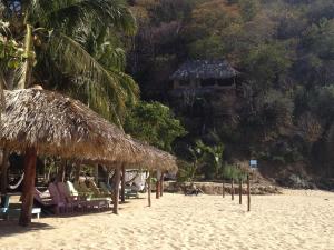 una playa con un montón de sillas y sombrillas en Casa Luna Playa en Puerto Ángel
