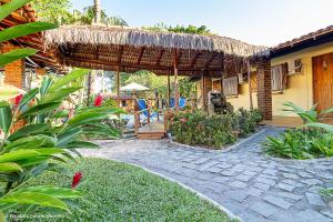 un patio con sombrilla de paja, mesa y sillas en Pousada Cavalo Marinho, en Arraial d'Ajuda