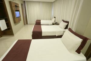a hotel room with two beds and a television at Esplanada Brasilia Hotel e Eventos in Brasília