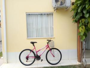 ein rosafarbenes Fahrrad, das vor einem Haus geparkt ist in der Unterkunft Residencial Praia dos Corais in Coroa Vermelha