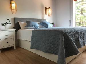 ein Schlafzimmer mit einem Bett mit blauen Kissen und einem Fenster in der Unterkunft Els Avets de la Muga in Sant Llorenç de la Muga