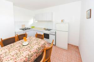 una pequeña cocina con mesa y nevera blanca en Apartments Goga, en Novalja