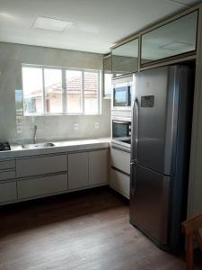 a kitchen with a stainless steel refrigerator and a sink at Apartamento Ponta do Papagaio - Com Varanda in Palhoça