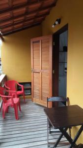 a porch with two red chairs and a wooden table at Ao Mare in São Francisco