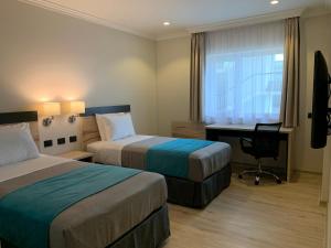 um quarto de hotel com duas camas e uma secretária e uma janela em Hotel Diego de Almagro Temuco Express em Temuco
