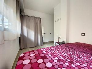 ein Schlafzimmer mit einem rosa Bett mit einem Polyka-Dot-Teppich in der Unterkunft F2 "Le parc" CLIM, WIFI, PMR in Balaruc-les-Bains