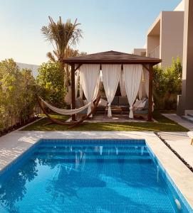 a pool with a hammock and a gazebo at The Sunshine Villa in Dubai