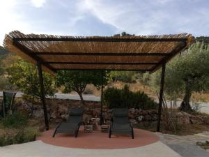 pérgola de madera con 2 sillas y mesa en Alojamiento Rural Alfaguara en Tolox