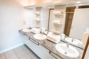 a bathroom with two sinks and two mirrors at Tahiti Airport Motel in Faaa