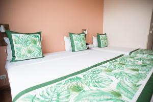 - un lit avec des draps et des oreillers verts et blancs dans l'établissement Tahiti Airport Motel, à Fa'a'ā