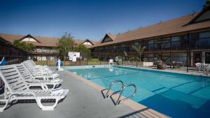 a pool with white lounge chairs next to a building at Best Western Andersen's Inn in Santa Nella