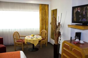 Zimmer mit einem Tisch, Stühlen und einem TV in der Unterkunft San Juan Park Hotel in San Juan del Río