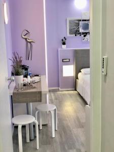 um quarto roxo com uma cama, uma mesa e cadeiras em BB Veronesi em Bolonha