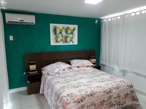 a bedroom with a bed and a green wall at Casa em Búzios in Búzios