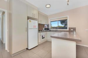 a kitchen with a white refrigerator and a window at Kennedy Holiday Villas in Mulwala