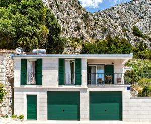 una casa con porte da garage verdi di fronte a una montagna di House Dunja a Omiš (Almissa)
