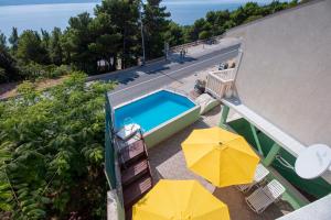 uma vista superior de uma piscina com dois guarda-sóis amarelos em Apartments Mirko em Lokva Rogoznica