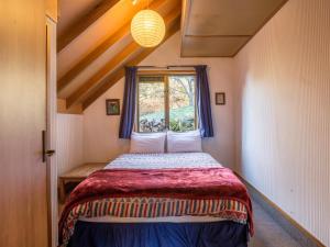 een kleine slaapkamer met een bed en een raam bij Evergreen Haven - Queenstown Holiday Home in Queenstown