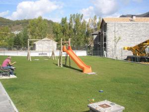 a playground with an orange slide in a yard at Apartamentos Portal de Ordesa in Fiscal