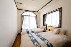 two beds in a room with two windows at with-terrace (Umi) in Kohama