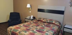 Habitación de hotel con cama y silla en Deluxe Inn Nebraska City en Nebraska City