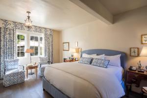 a bedroom with a bed and a chair and a window at L'Auberge Carmel, Relais & Chateaux in Carmel