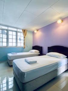 - 2 lits dans une chambre aux murs violets et aux fenêtres dans l'établissement Habitat Fraser's Hill, à Bukit Fraser