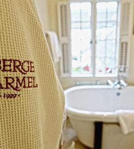 a white towel hanging on the side of a white bath tub at L'Auberge Carmel, Relais & Chateaux in Carmel