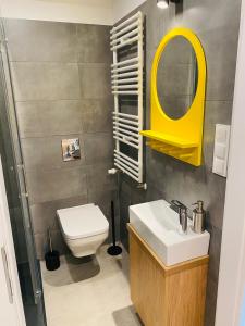 a bathroom with a toilet and a yellow mirror at Apartament Nowy Verdon Ruda Śląska in Ruda Śląska