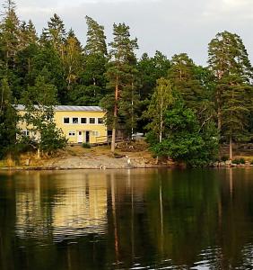 a yellow building on the shore of a lake at Vårhaga Vandrarhem in Sjuntorp