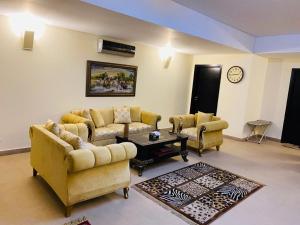 ein Wohnzimmer mit Sofas, einem Tisch und einer Uhr in der Unterkunft Royal Two Bed Room Luxury Apartment Gulberg in Lahore