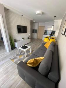 a living room with a gray couch and yellow pillows at Apartament Mateusz in Świnoujście