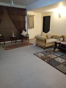 Royal Two Bed Room Luxury Apartment Gulberg في لاهور: غرفة معيشة مع أريكة وكراسي وسجادة