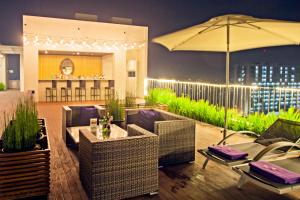a patio with wicker chairs and tables and an umbrella at Swiss-Belinn Cikarang in Cikarang