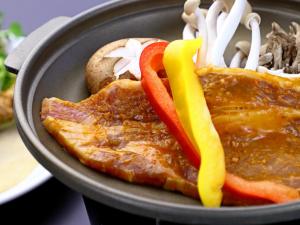 une assiette de nourriture avec de la viande à base de poivrons et de nouilles dans l'établissement Echigoya Ryokan, à Ogano