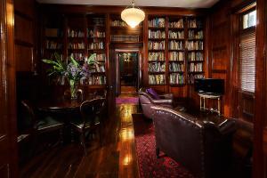 a library with leather chairs and a table and books at The Regents Park in Maitland