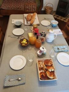 een tafel met een ontbijt van croissants, brood en sap bij Le jardin des gouttes in Rougegoutte