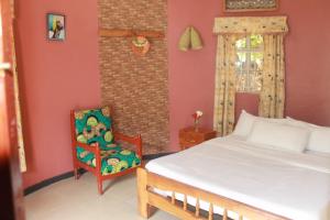 een slaapkamer met een bed en een stoel bij Crater Bay Cottages in Kabale