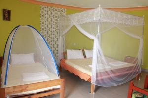 a bedroom with two beds and a canopy bed at Crater Bay Cottages in Kabale