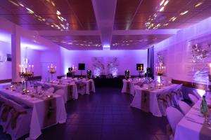 a banquet room with white tables and chairs and purple lighting at Château de Petit Bois in Cosne-dʼAllier