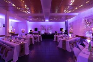 une salle de banquet avec des tables et des chaises blanches et un éclairage violet dans l'établissement Château de Petit Bois, à Cosne-dʼAllier